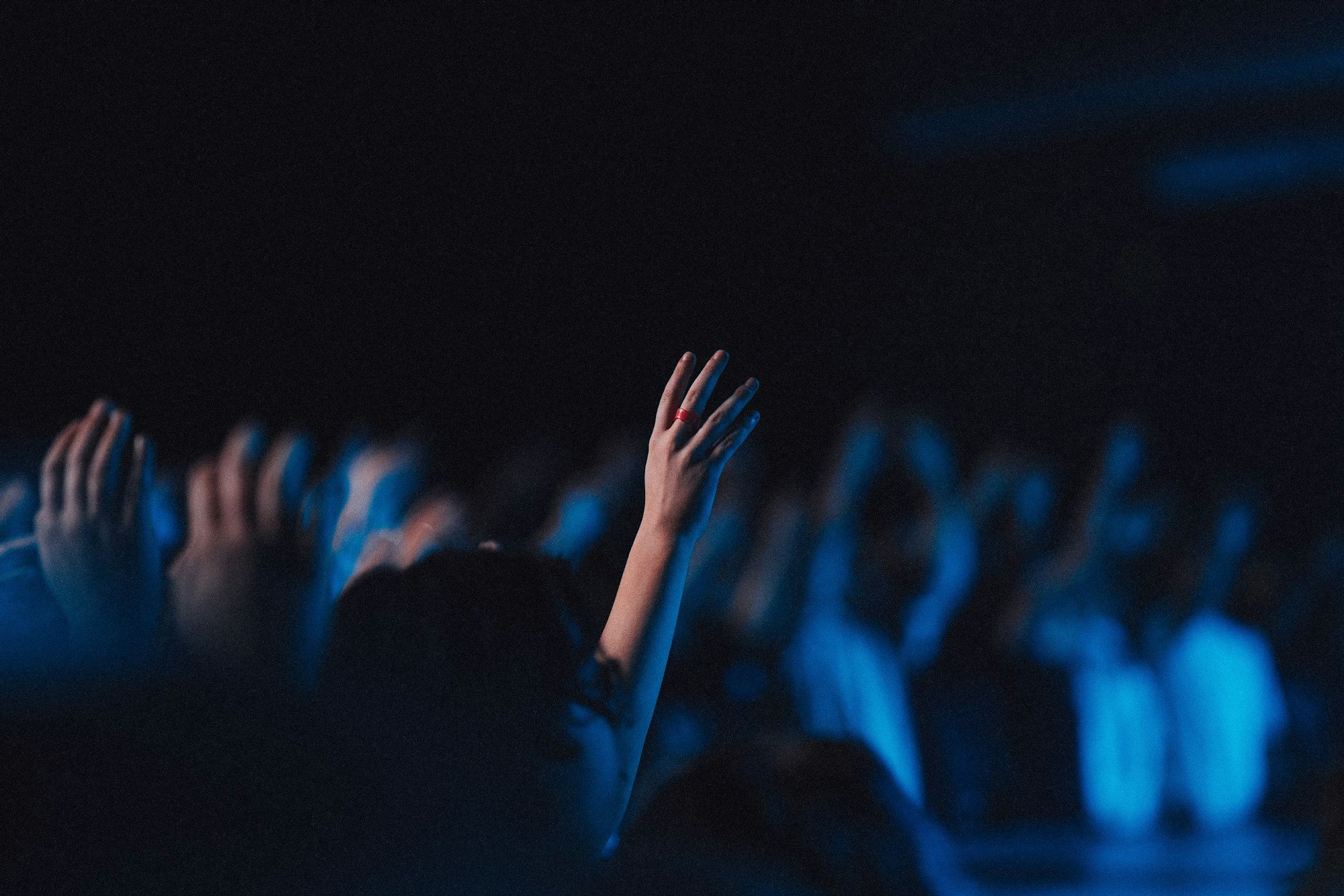 Believers in worship gathered in a hall with blue light effect